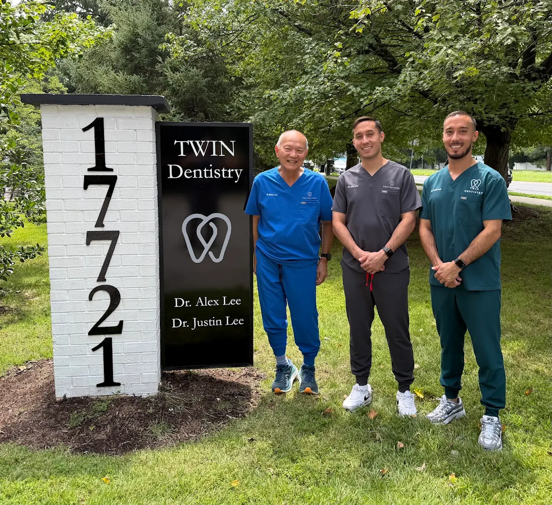 Dr. Henry Lee, Dr. Alex Lee, and Dr. Justin Lee standing beside the Twin Dentistry sign and the 17721 address pillar on Georgia Avenue in Olney